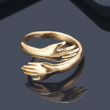 goldener fingerring mit händen die umarmen