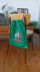 Turnbeutel mit Kordeln grün präsentiert auf Vintage Stuhl